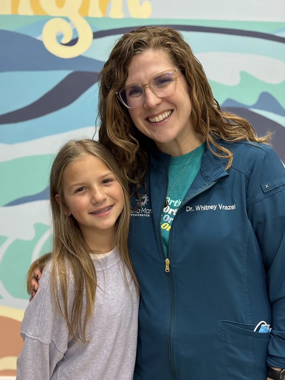 whitney vrazel and patient in front of mural