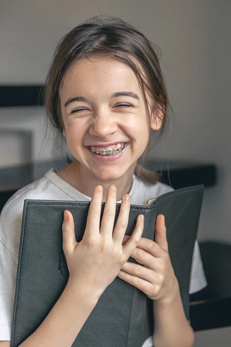 teenage-girl-reads-book-smiles-showing-her-teeth-with-braces